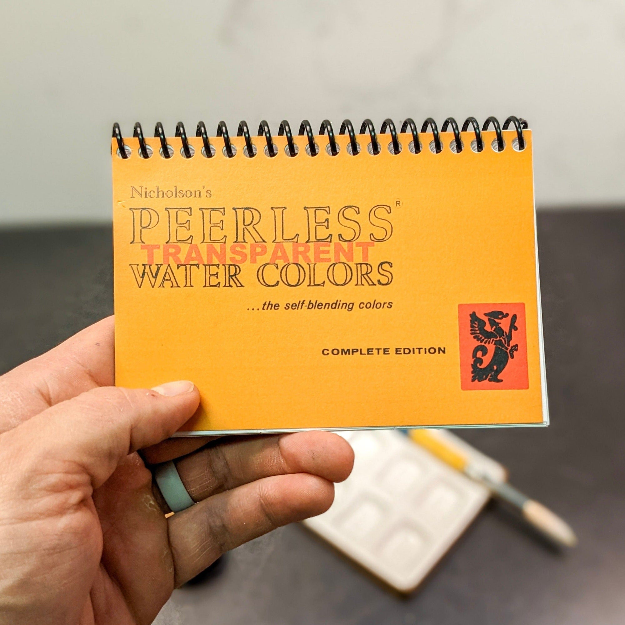 a mini version of our celebrated and popular Complete Edition portable watercolor palette shown in hand.