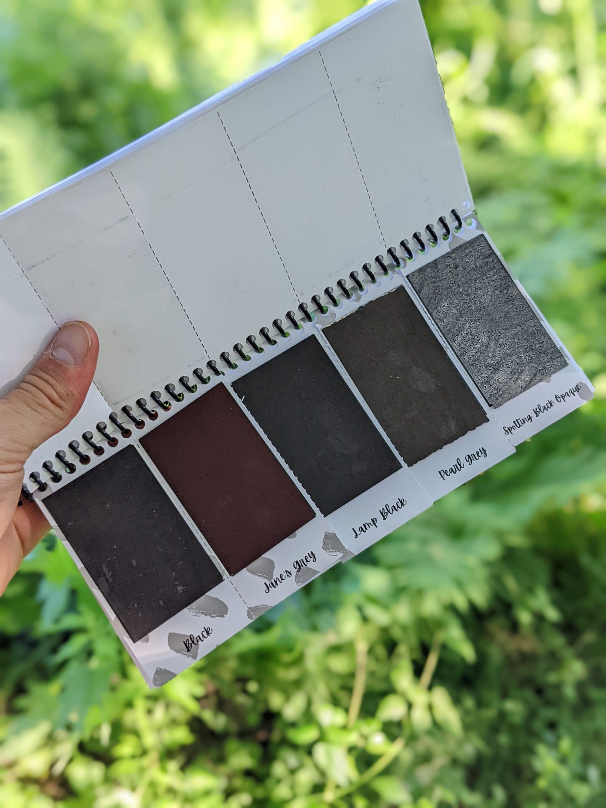 inside sheet of the peerless watercolors portable watercolor palette the Sidekick. This watercolor palette is super vibrant, portable, and easy to use.  this picture is showing of the black and grey paints included in the travel watercolor palette.