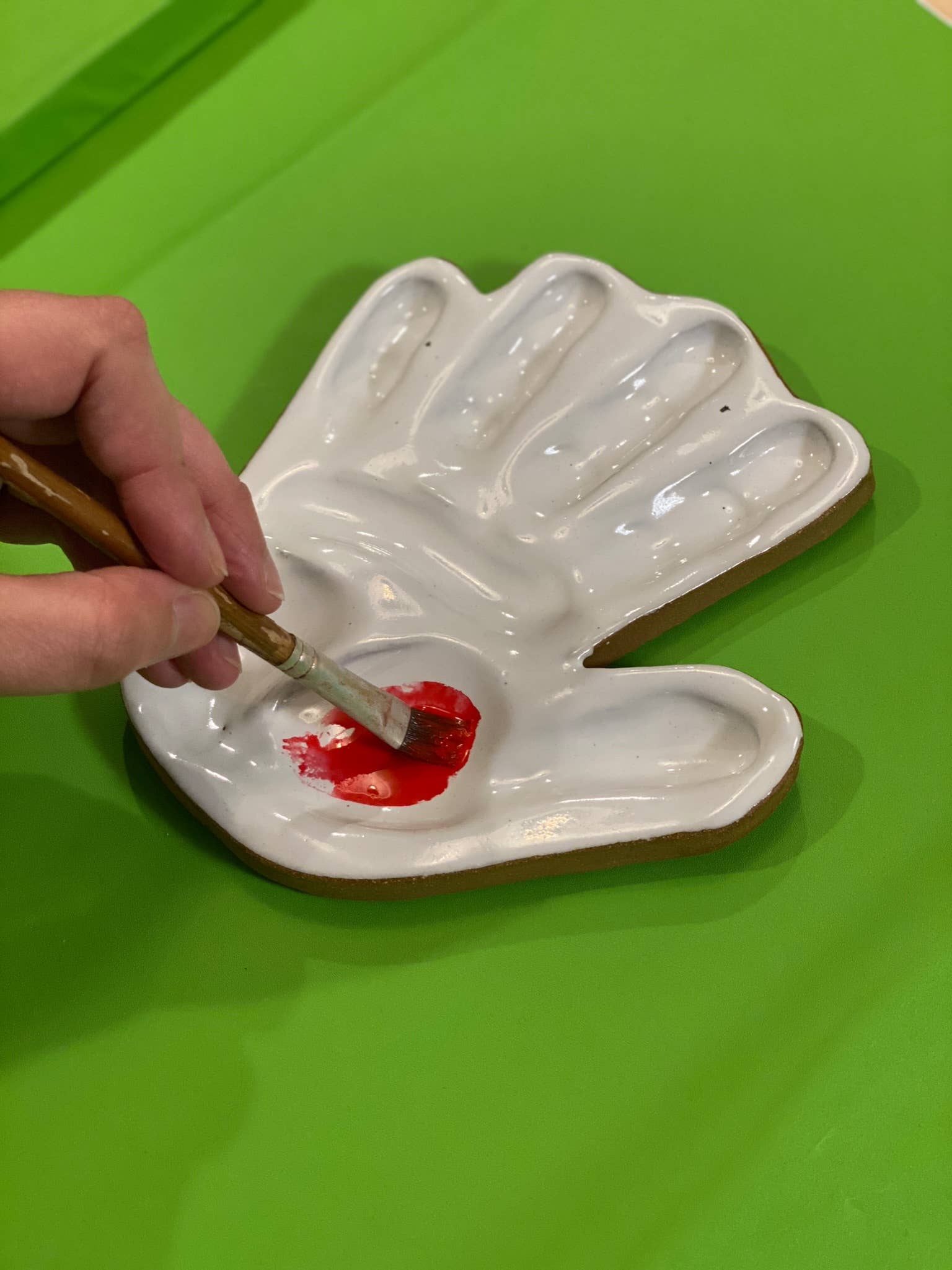 hand made, ceramic palette, modeled after the hand of the artist that made the watercolor mixing palette being used with a watercolor brush and paint