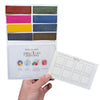 A hand holds a Urban Sketcher Starter Palette - a  Peerless Watercolors custom palette including 8 handpicked colors, an instructions card and a swatch card.